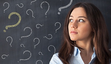 Woman in front of chalkboard with question marks